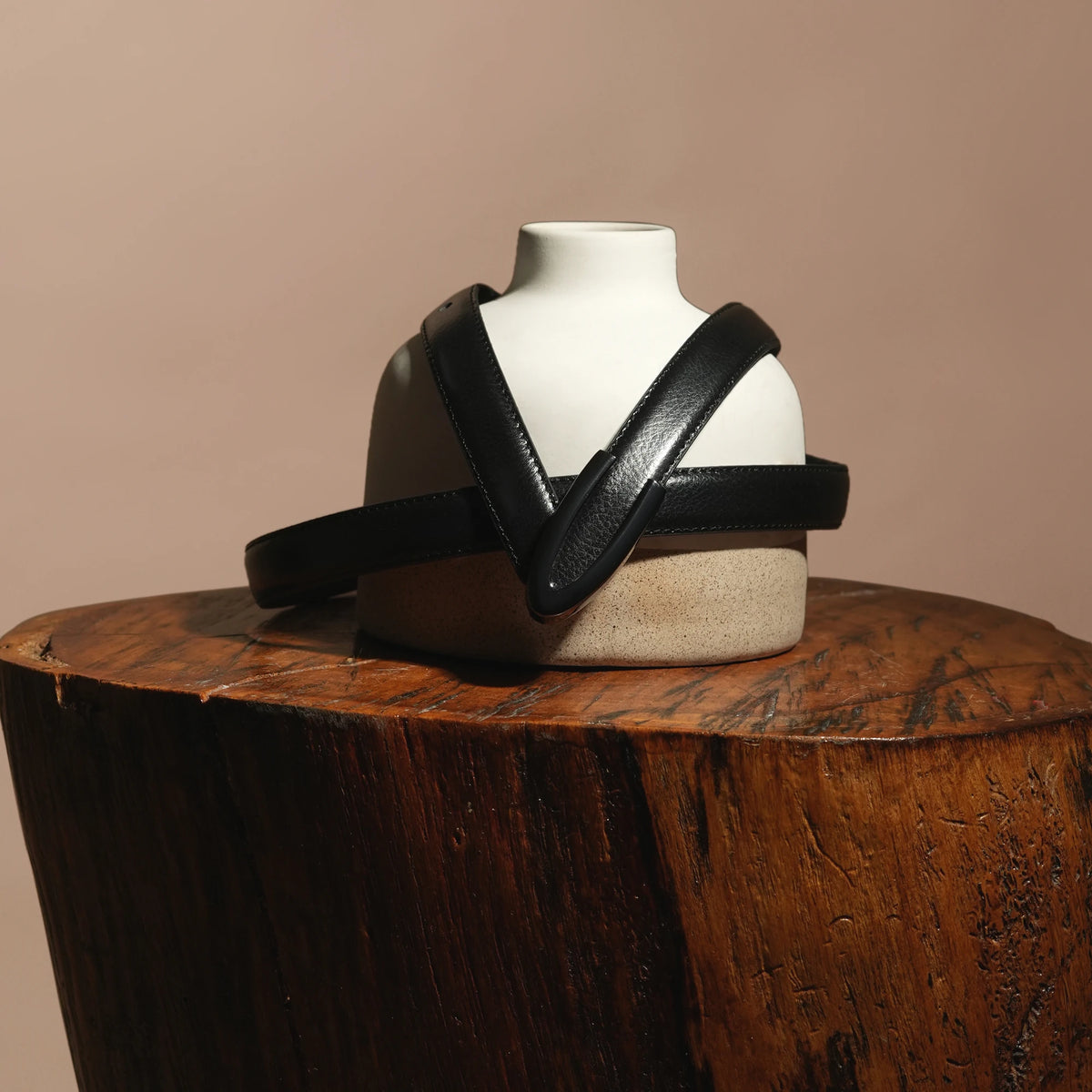 Darci belt draped over a ceramic bust on a wooden stump