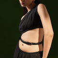 Woman in a black one-shoulder cut-out top wearing the black Darci belt