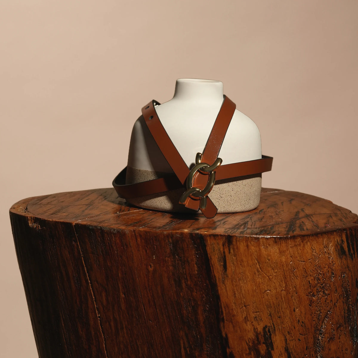 Scarlett brown belt draped over a ceramic bust on a wooden stump