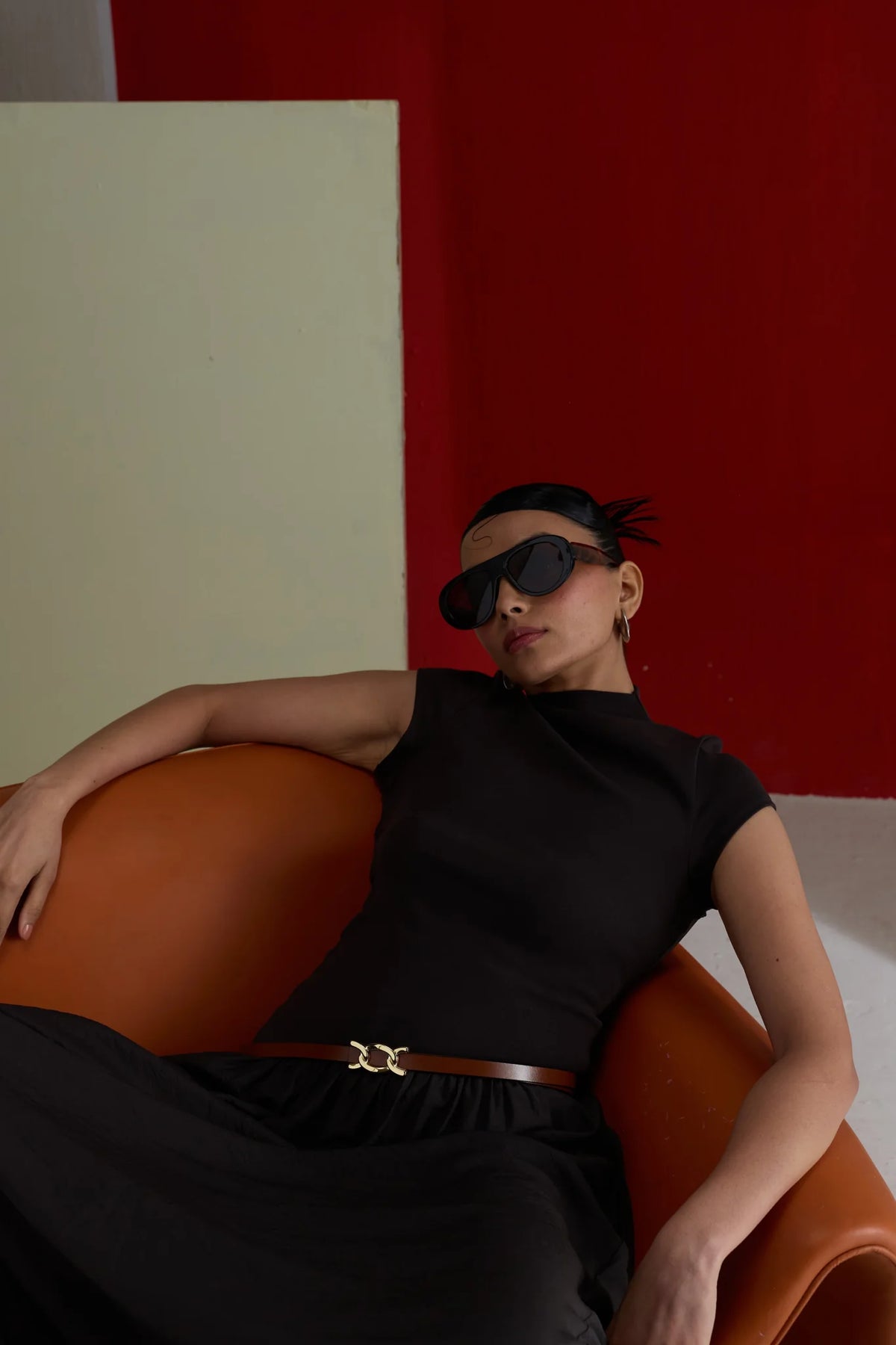 Woman lounging on a leather chair wearing the brown Scarlett belt