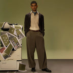 Man in a brown cardigan and olive trousers wearing the Savora belt brown side out by a photocopier